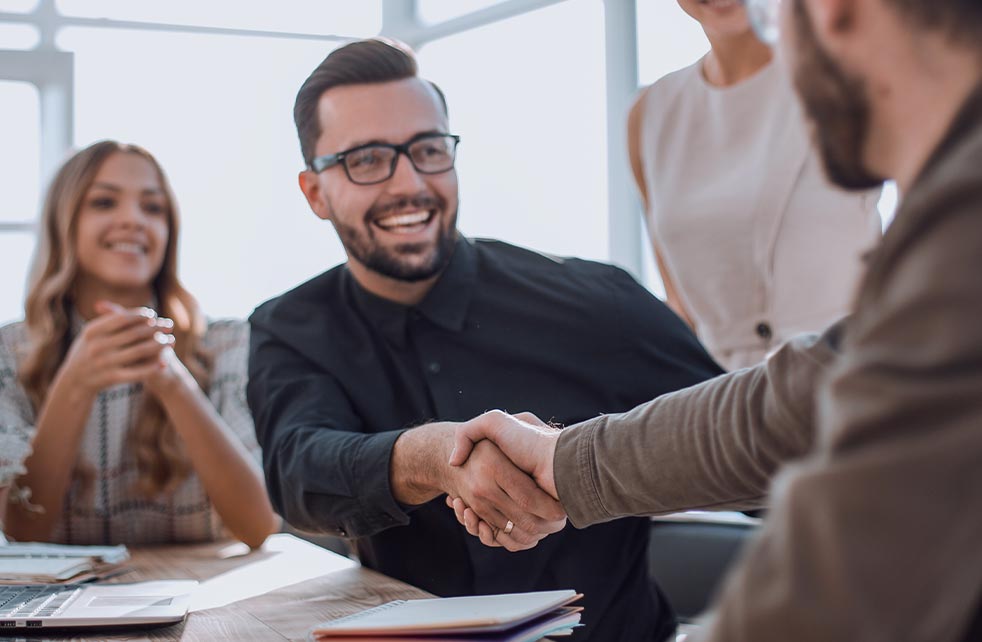 Man smiling and shaking hands with someone else